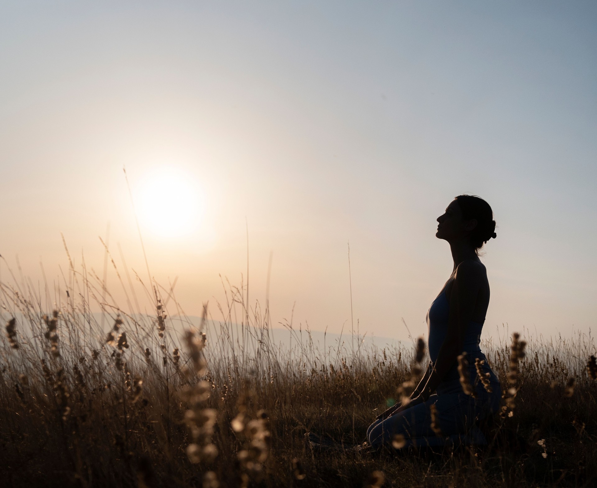 Silhouette of woman practicing yoga outdoors